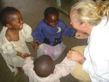 A medical student in white coat with three young African children