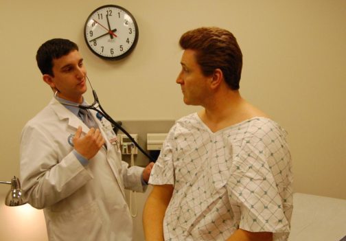 Student using a stethoscope on a patient.