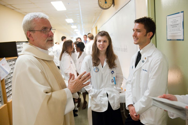 SOM students talking to a Georgetown University Jesuit.