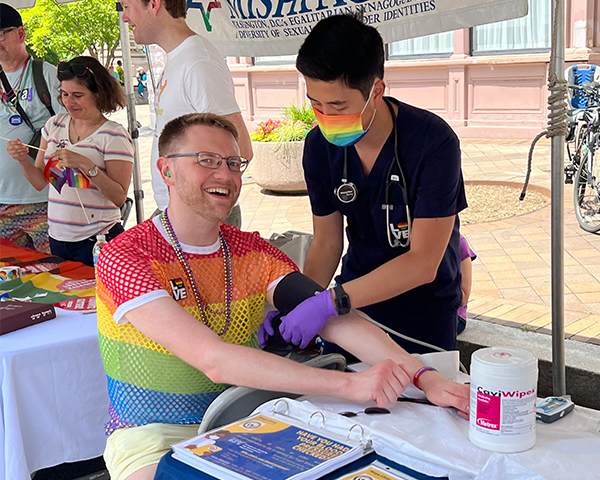 A student places a blood pressure cuff around the arm of a Capital Pride participant