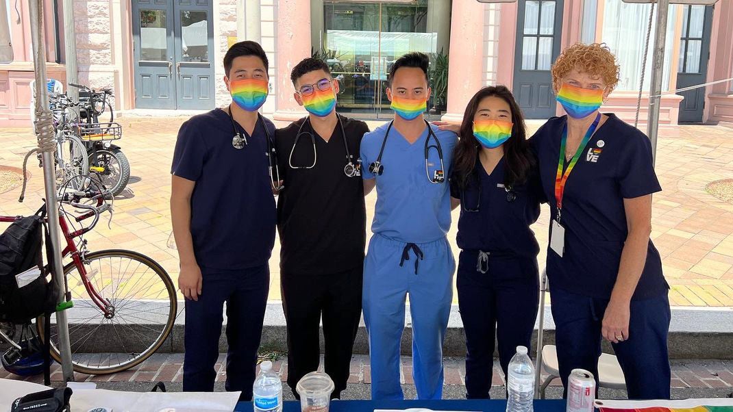 Five individuals stand together behind a table at Capital Pride