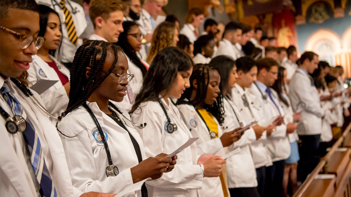 Medical students stand and recite the Hippocratic Oath at the White Coat Ceremony