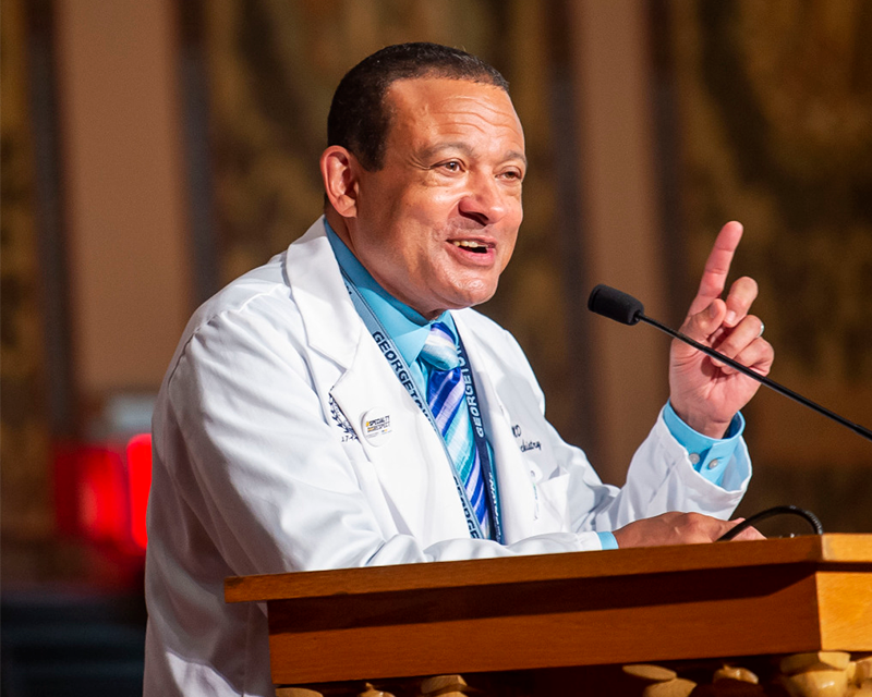 Lee Jones speaks from a podium at the White Coat ceremony