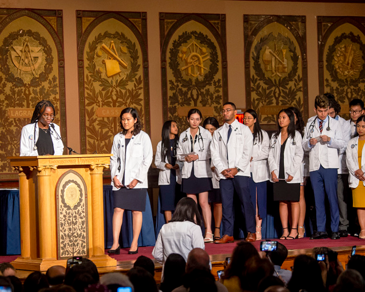 Students line up to speak at a podium during the White Coat Ceremony