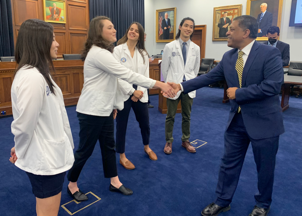 A student shakes hands with a Congressional staffer while other students look on