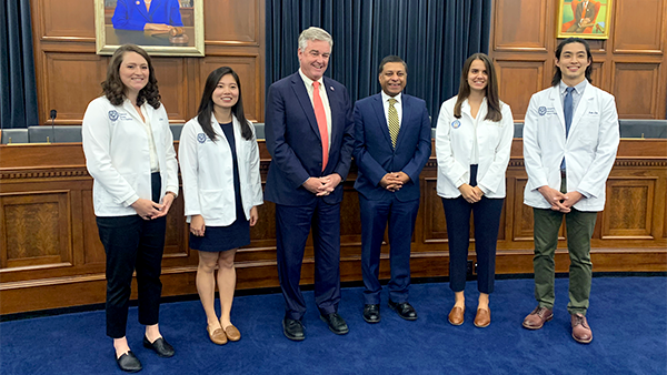 Four medical students stand with two Congressional staffers in a group