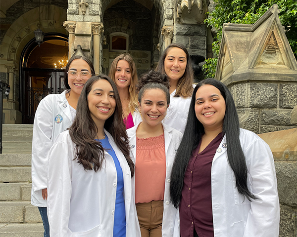 Six medical students stand together on the steps of Healy Hall