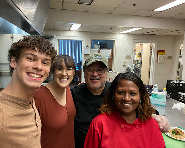 Students and cooking staff stand together in a kitchen