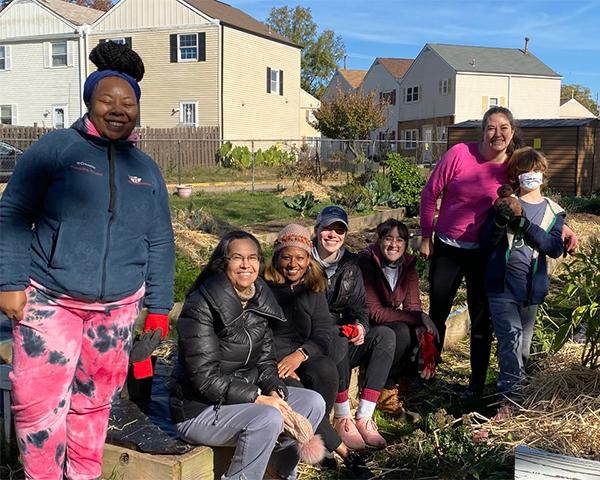 A group stands and sits amid raised beds in the NCC garden