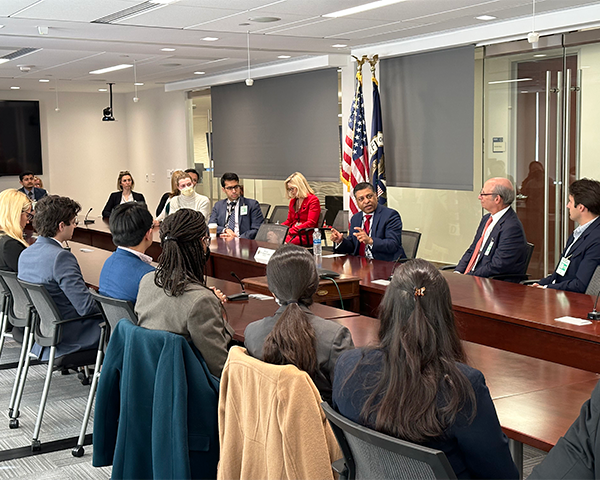 Dr. Gupta speaks to a table lined with medical students and their professor