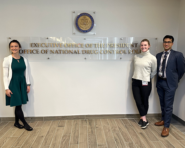 Three students stand near a sign that reads Executive Office of the President Office of National Drug Control Policy