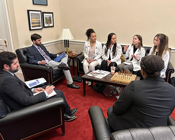 Students sit on a couch and talk with congressional staffers who are seated in individual chairs