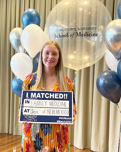 Whitney Peterson holds a sign that reads I Matched!! in Family Medicine ta Univ of New Mexico