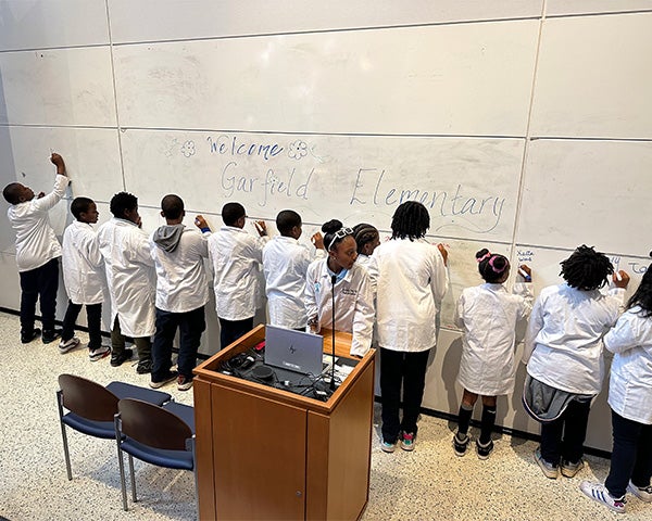 Students line up to sign a whiteboard behind the podium