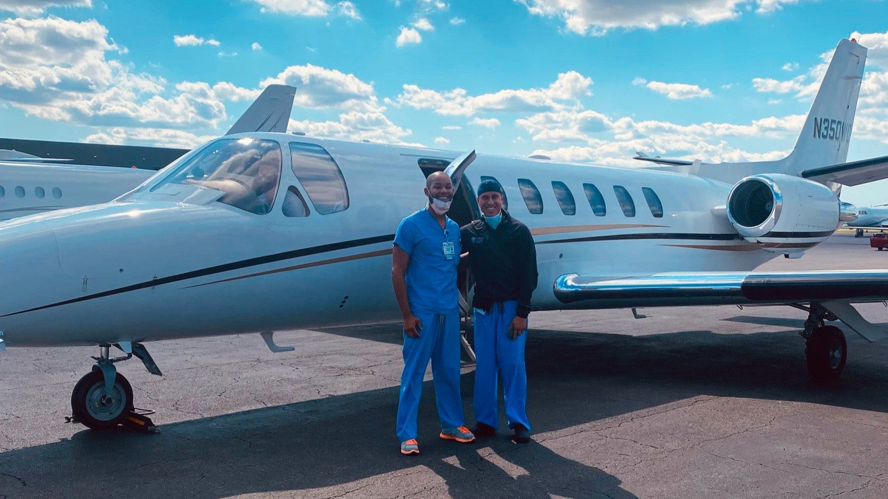 Malcom Meredith and Dr. Aguirre stand outside a small jet at an airport