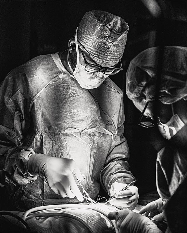 Malcolm Meredith in surgical garb performing a surgical procedure