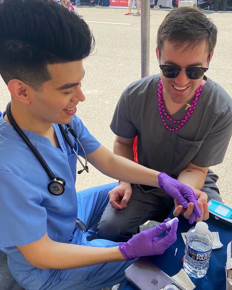 David Perez pricks the finger of a fellow volunteer