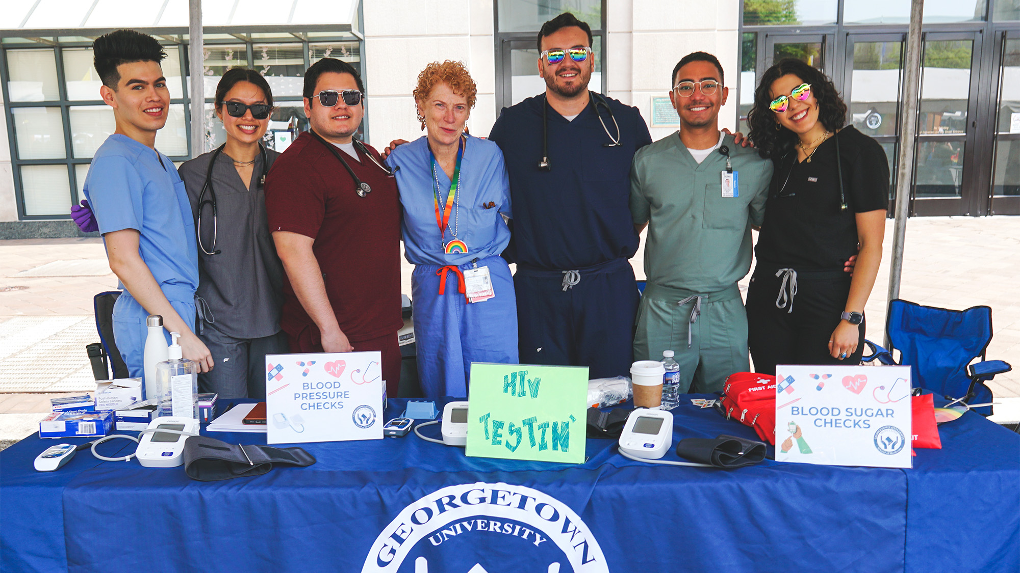 A group of medical students stands with Dr. Moore at the table they set up at the Pride Festival