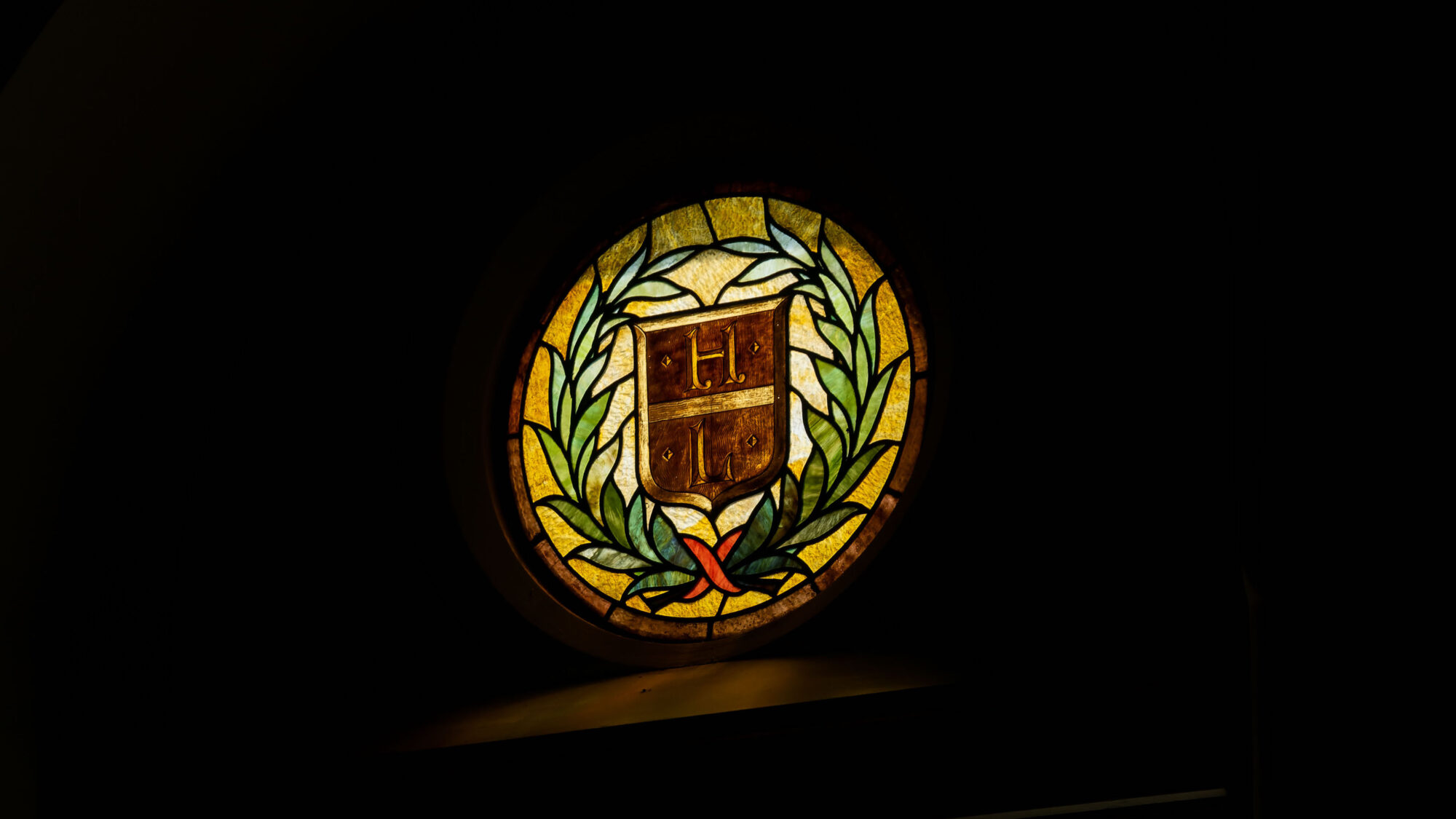 A stained glass window is colorful against a dark background