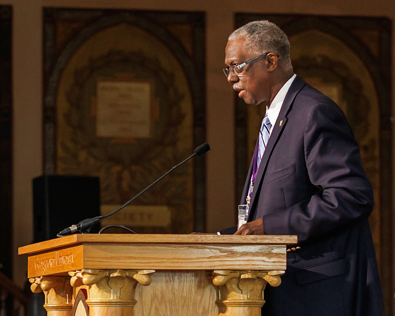 Earl Harley stands at a podium onstage in Gaston Hall