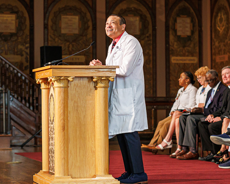 Dr. Jones speaks at a podium onstage in Gaston Hall