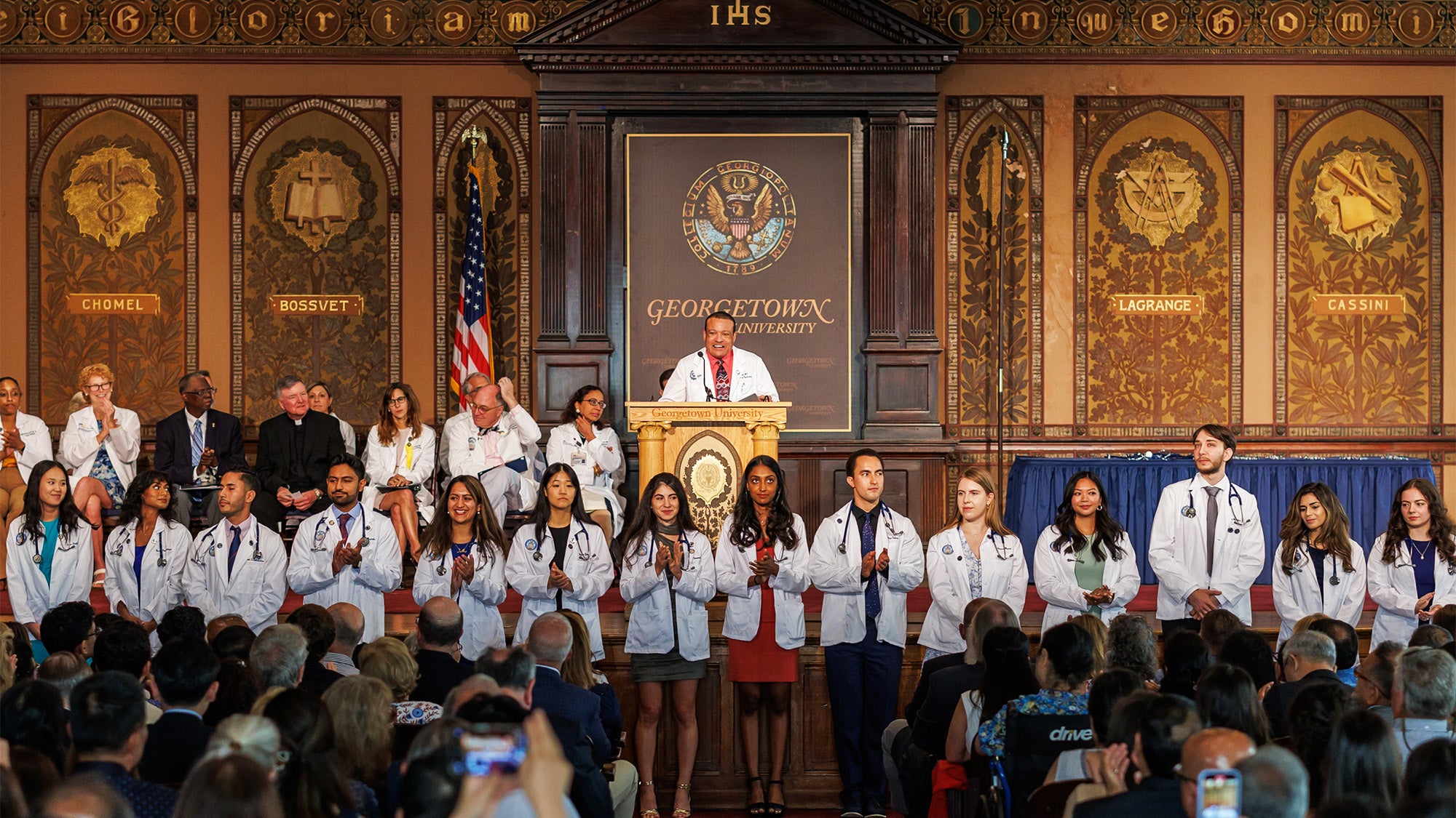 Students line up before the stage on which faculty are standing and applauding them in Gaston Hall