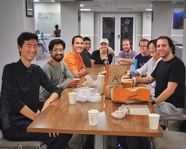 A group of MD/PhD students sits around a table at a bagel shop