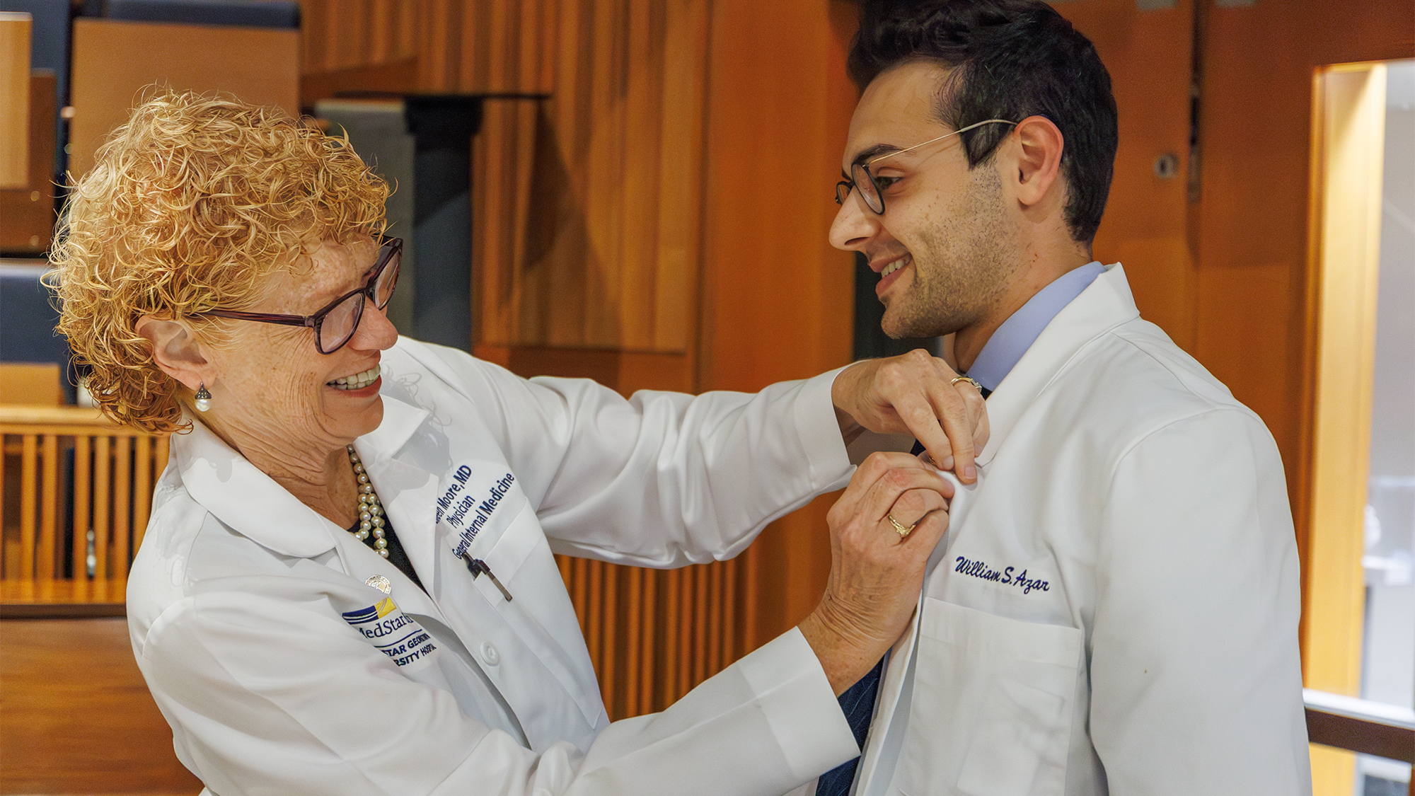 Dr. Moore pins an award onto the white coat of student William Azar