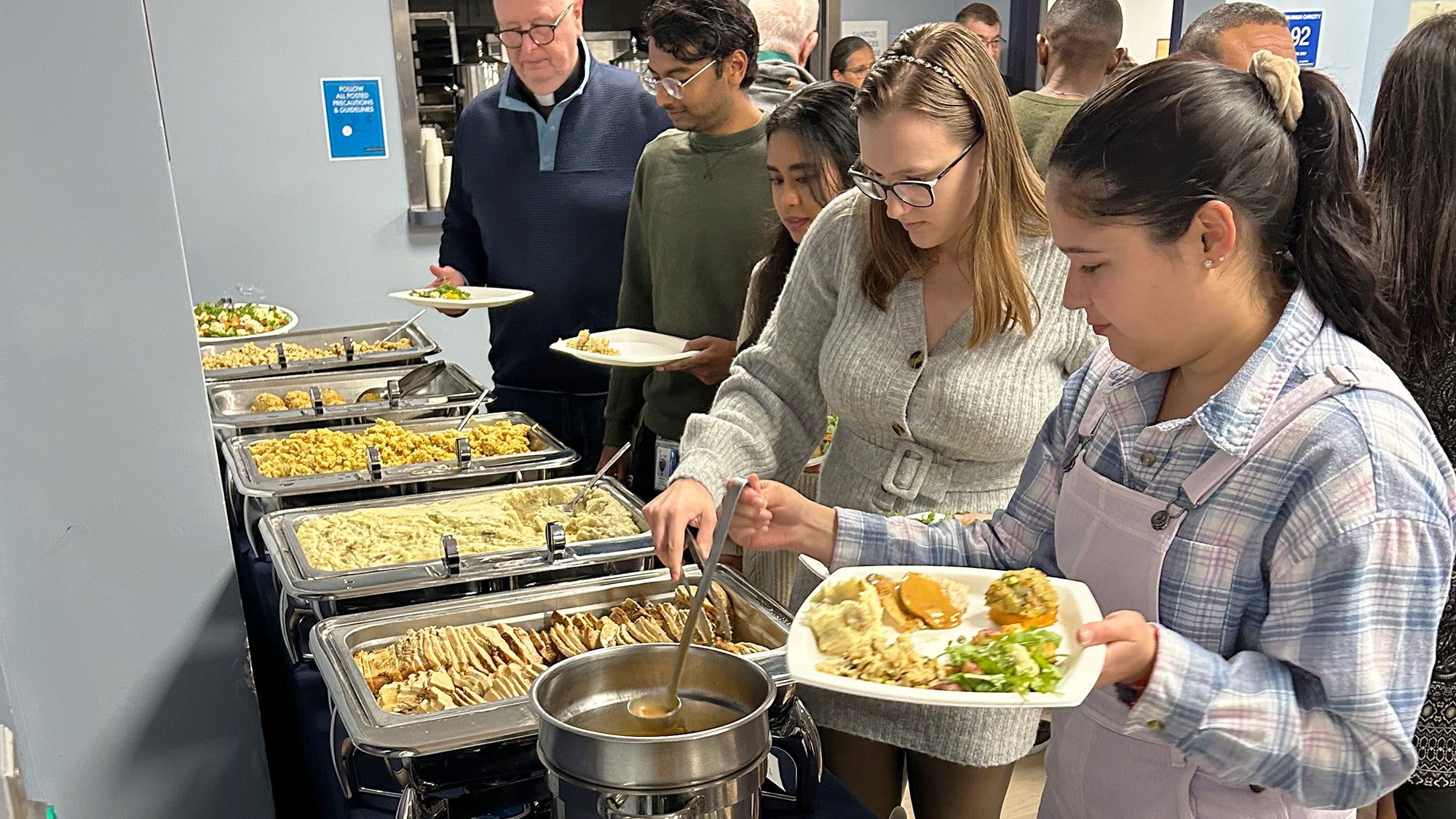 Students and faculty dish themselves food from various serving trays