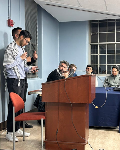 A student stand behind a podium and leads a prayer