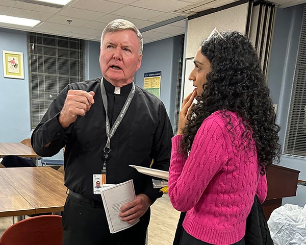Father Shea speaks with a female student