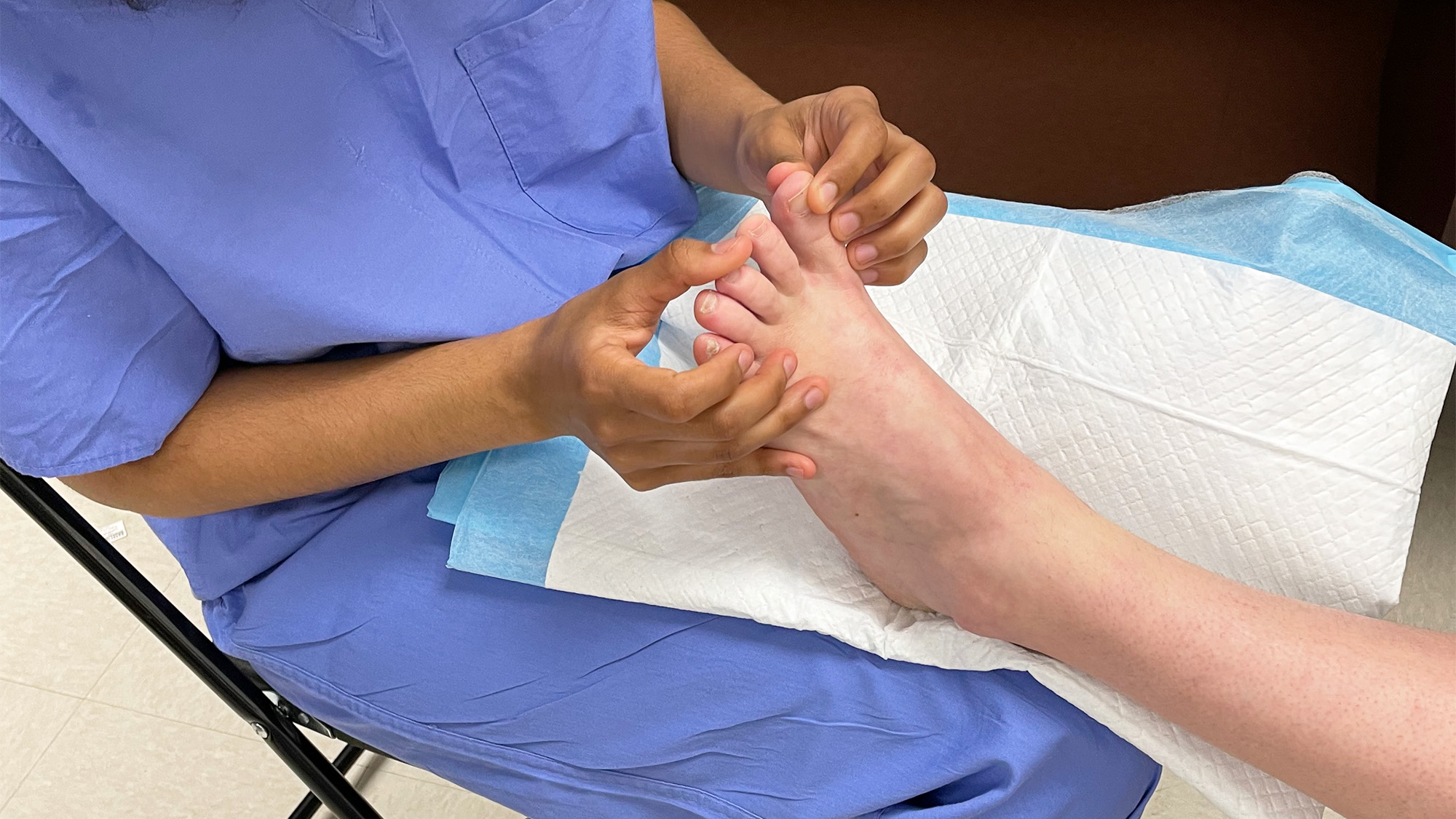 A medical student holds a patient's foot during an exam