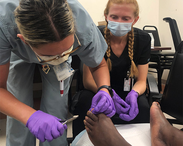 Two medical students attend to a client's foot