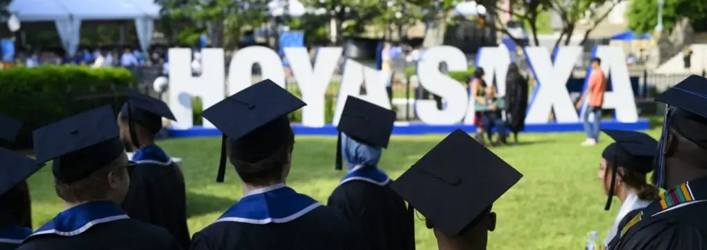 Graduating students near the Hoya Saxa sign on campus