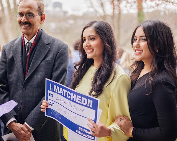 Two individuals flank a medical student holding a sign that reads I Matched in Internal Medicine at Georgetown