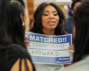 A student holds a sign that reads I matched in dermatology at Howard