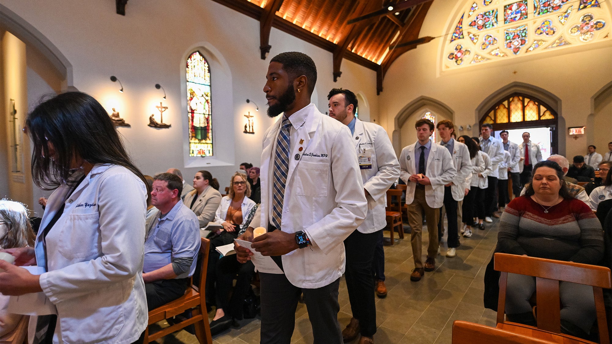 Medical students process into Dahlgren, which is full of congregants