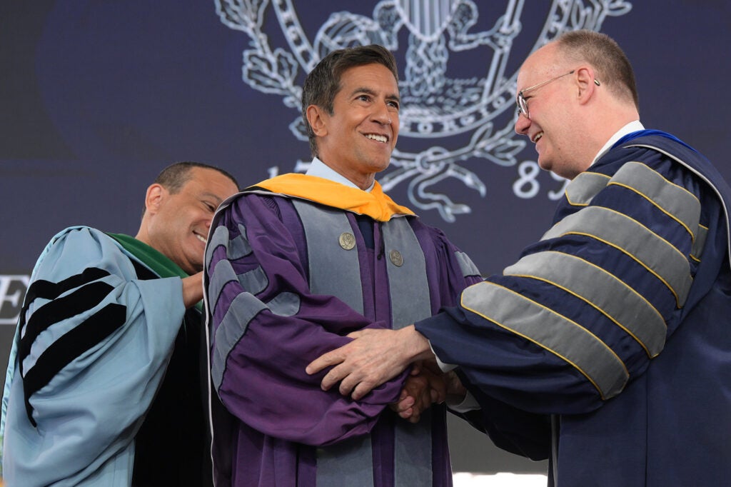 Dean Jones and President DeGioia place a yellow hood over the shoulders of Sanjay Gupta, MD.