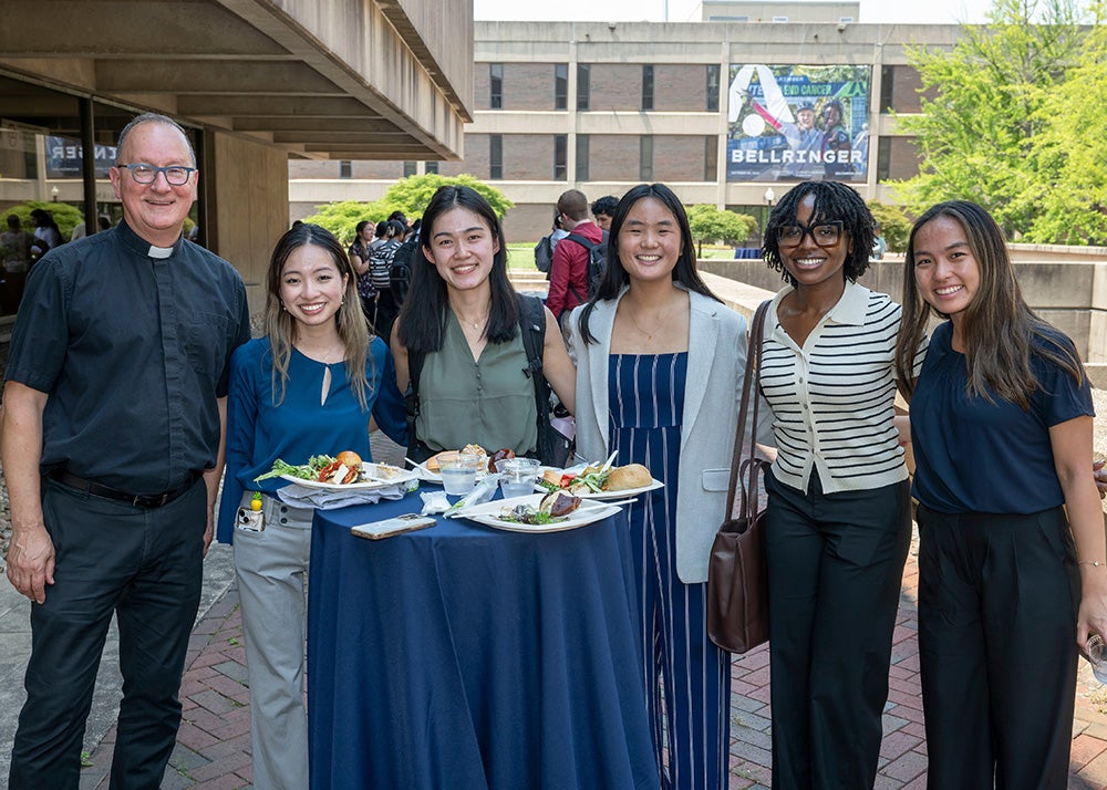 Father Bosco stands with five medical students