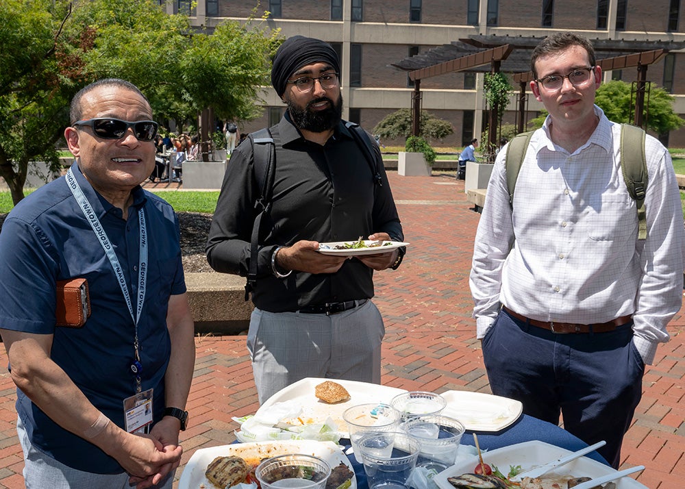 School of Medicine dean Lee Jones stands with two students at a table laden with plates of food