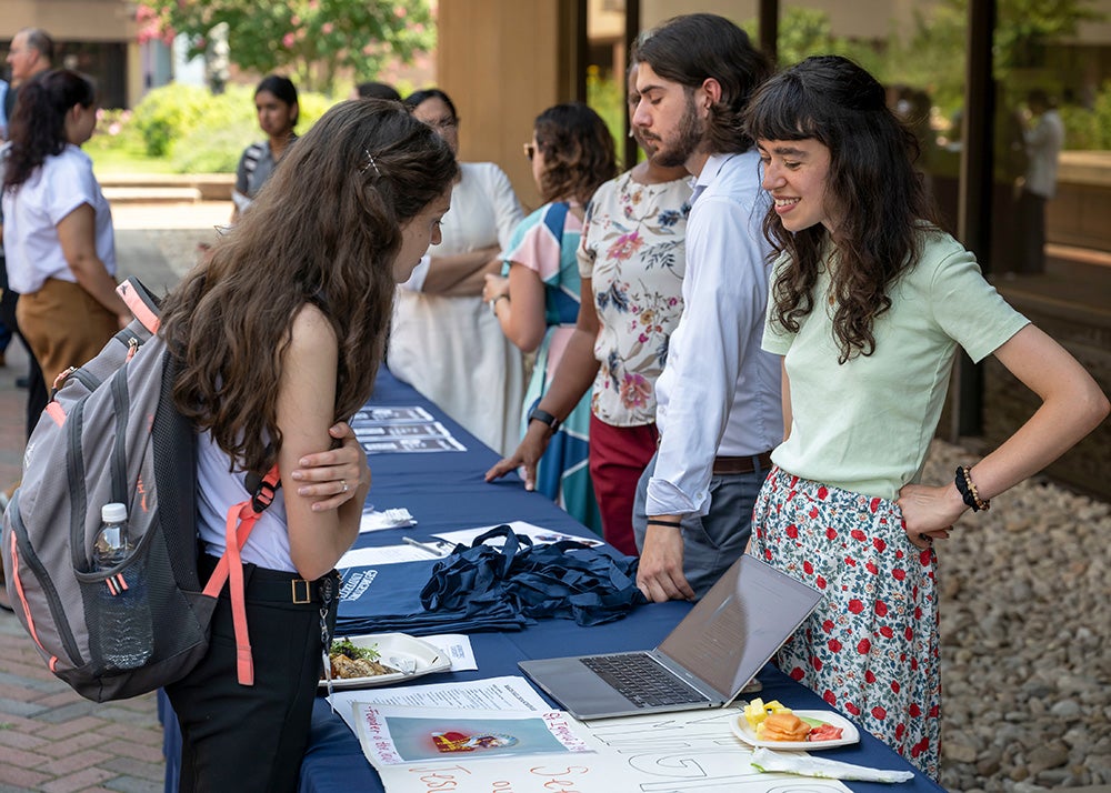 Students speak with representatives of various faith organizations on campus at a long table