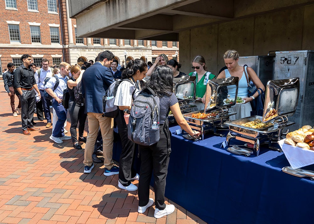 Medical students line up along a buffet of food