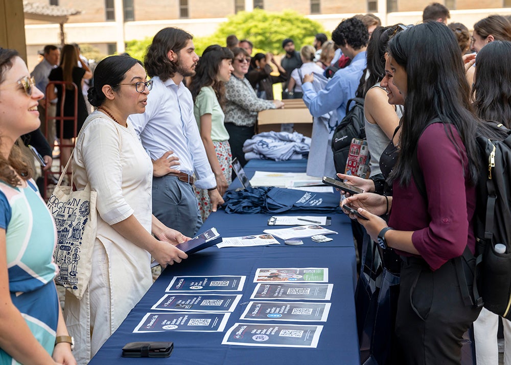 Students speak with various faith organization representatives lined up at a table