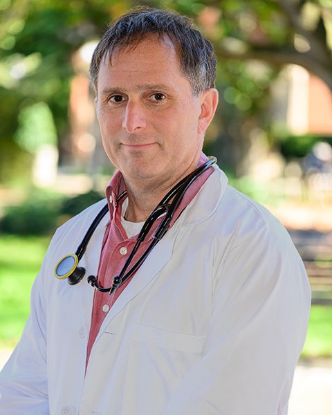 Dan Merenstein wears his white doctor's coat and stethoscope in an outdoor setting