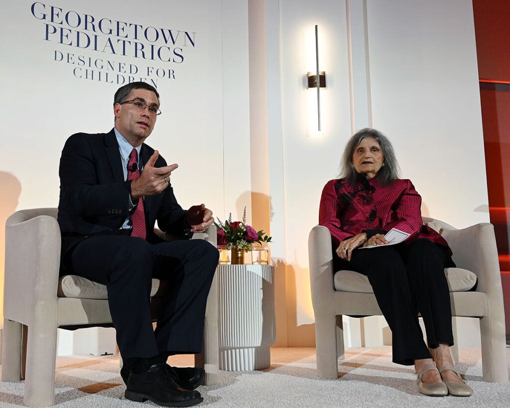 Dr. Donnelly and Dr. Magrab sit in chairs on a stage at the gala