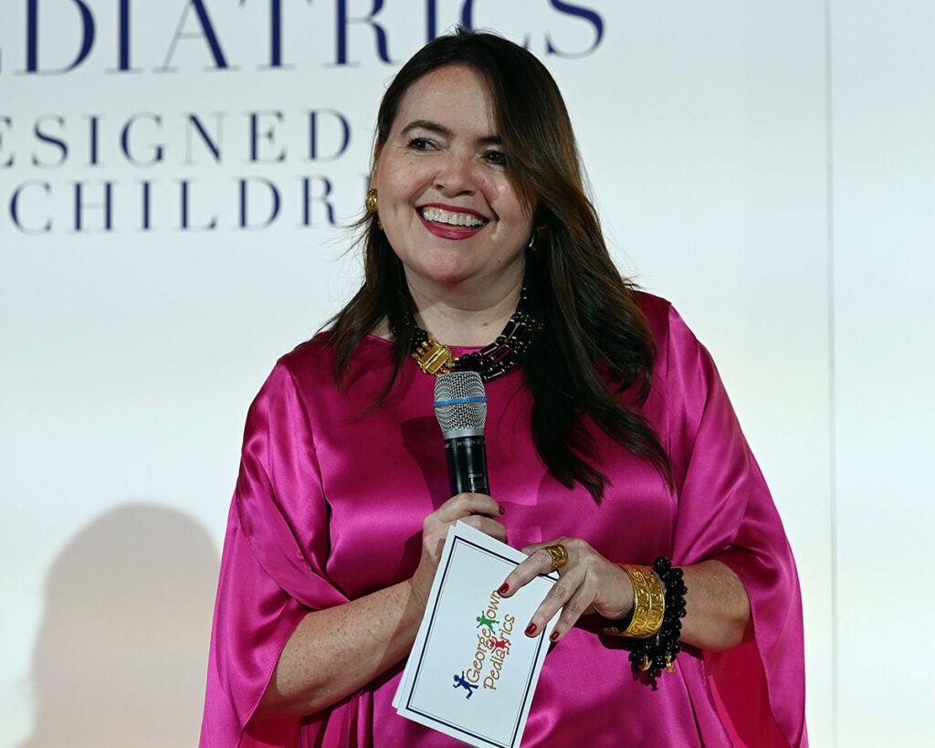 Dr. Serrano holds a microphone onstage at the gala