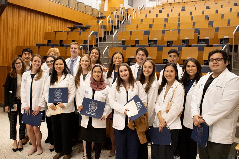 The new student members of the society and some faculty stood together in an auditorium setting