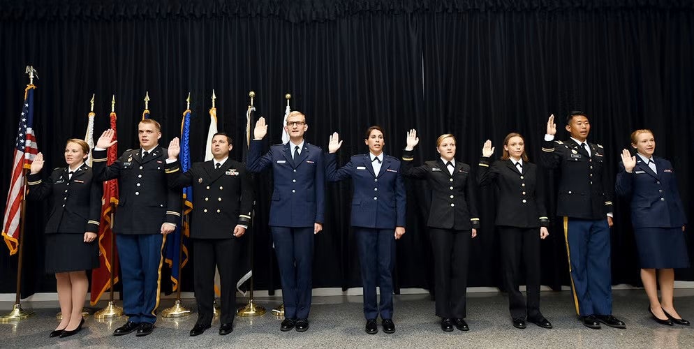 Graduating medical students raise their right hands to take the oath as they enter into military service