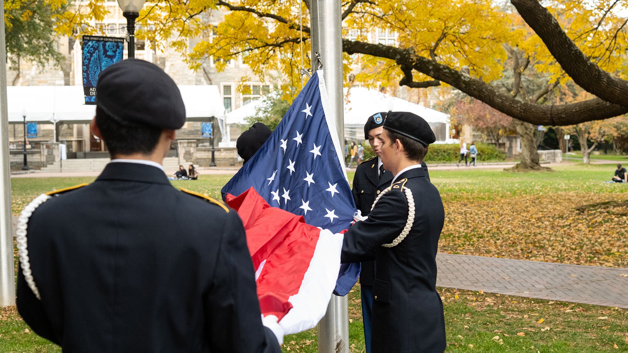 Students in military uniform raise the American flag as part of the annual Veterans Day ceremony