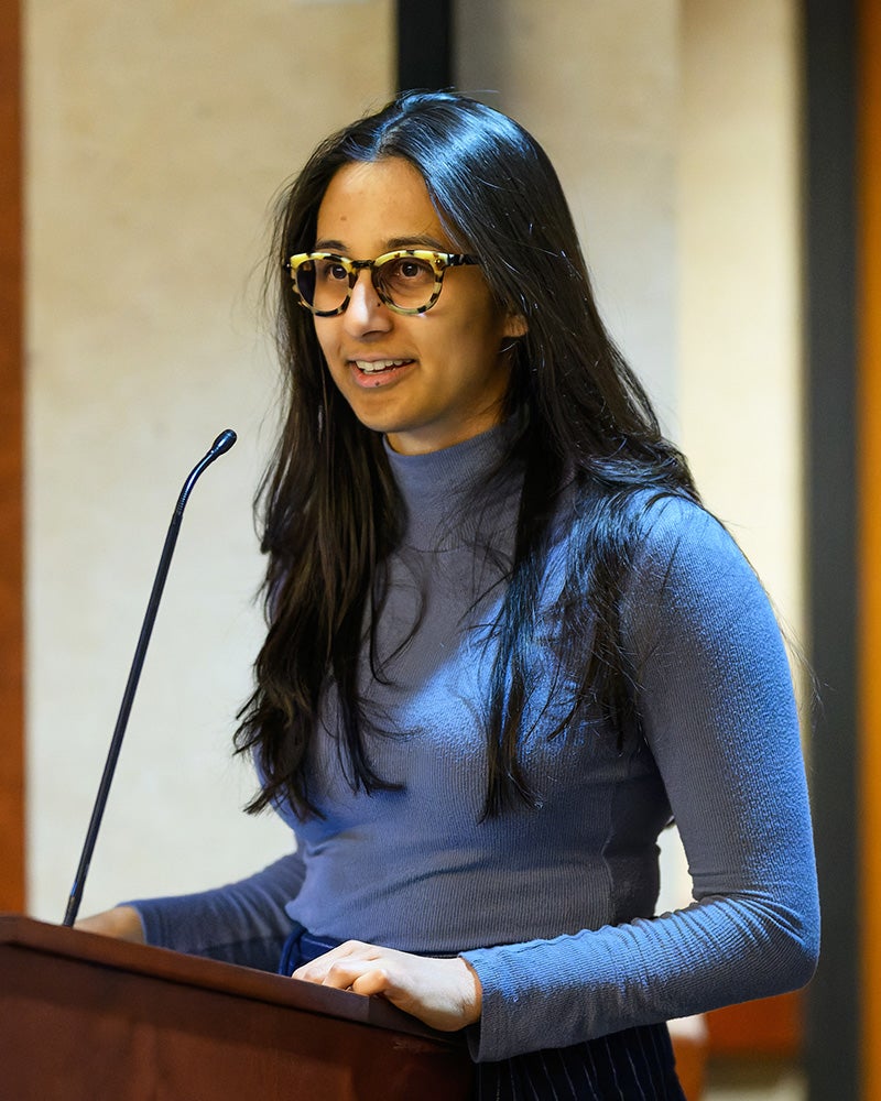 Arya speaks from behind a podium